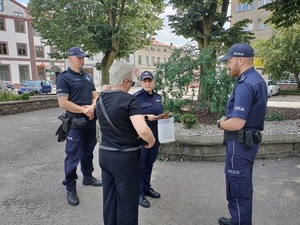 Trójka umundurowanych policjantów rozmawia z kobietą na ulicy