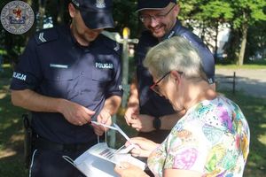 Dwóch umundurowanych policjantów rozmawia z kobietą