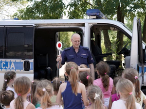 Policjant z grupą dzieci przy radiowozie typu bus