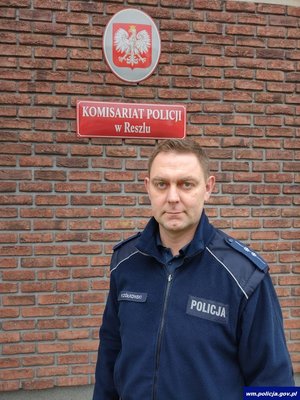 Policjant na tle budynku komisariatu