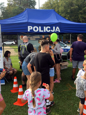 Piknik z udziałem młodzieży na pierwszym planie namiot i radiowóz policyjny