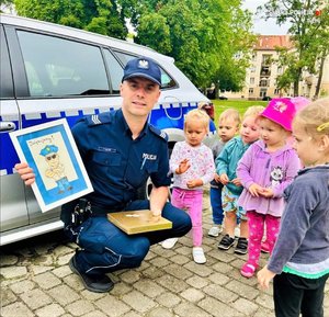 Policjant z dziećmi obok radiowozu