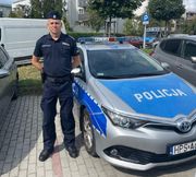 Umundurowany policjant stojący przy radiowozie