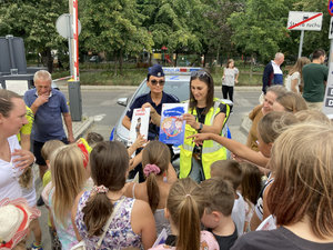 Policjantka obok radiowozu oraz tłum dzieci