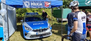 Namiot wystawienniczy policji, w którym stoi radiowóz obok ubrani w stroje sportowe rowerzyści