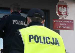 Policjanci z zatrzymanym wchodzący po schodach komisariatu