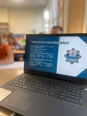 zdjęcie przedstawia laptopa z wyświetlonym slajdem prezentacji o przyczynach demoralizacji w czasie spotkania policjantów z uczniami