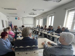 W pomieszczeniu osoby siedzące przy stole