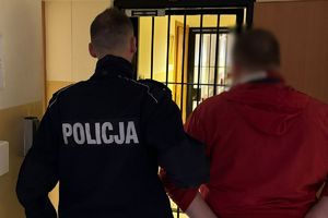 W pomieszczeniu policjant prowadzi zatrzymanego