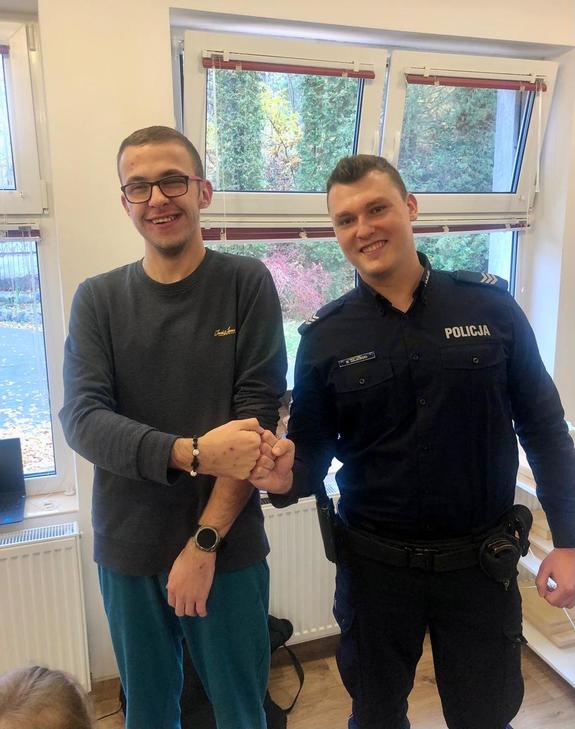 Policjant i młody mężczyzna pozujący do zdjęcia na tle okna