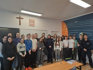 Młodzież pozująca w sali szkolnej do zdjęcia, wśród niej dwójka policjantów