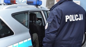 Policjant umieszczający mężczyznę na tylnym siedzeniu radiowozu