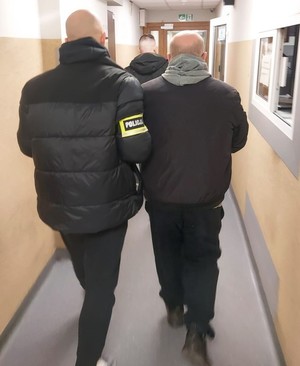 Policjant w cywilnym ubraniu prowadzi zatrzymanego