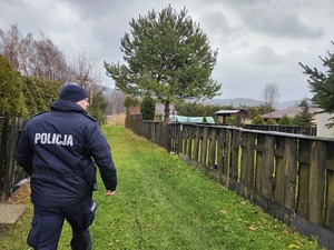 Policjant idący alejką działkową