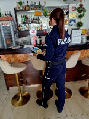 Widziana z tyłu policjantka w sklepie z alkoholami