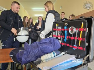 Sala szkolna, na pierwszym planie otwarta walizka kryminalistyczna, dalej policjant i młodzież