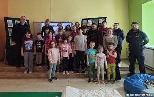 Młodzież pozująca z nauczycielką i dwoma policjantami do zdjęcia w klasie