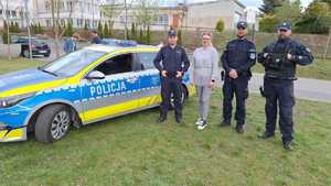 Trzech policjantów oraz kobieta przebrana za myszkę pozujący zdjęcia przed budynkiem szkłu na tle radiowozu