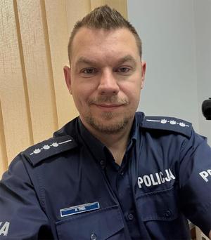 Uśmiechnięty policjant na tle wertykali