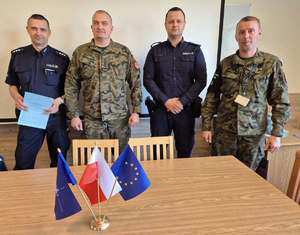 Dwaj policjanci oraz dwaj żołnierze pry stole konferencyjnym