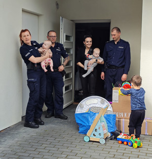 Trójka policjantów raz kobieta z dziećmi na rękach