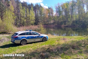 Radiowóz nad brzegiem stawu w lesie