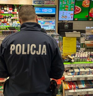 Widziany od tyłu policjant na tle regałów sklepowych