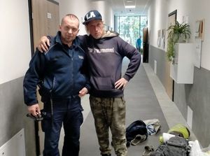 W korytarzu policjant oraz mężczyzna w bluzie i czapce z daszkiem
