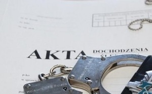 Okładki akt dochodzenia z leżącymi na nich kajdankami