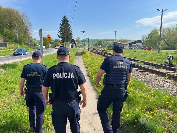 Idący ścieżką wzdłuż torów klejowych dwaj strażnicy SOK oraz policjant