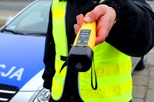 Policjant trzymający alkotest na tle radiowozu