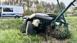 Rozbity na siatce ogrodzeniowej samochód osobowy, w tle radiowóz