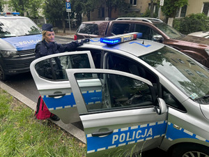 Policjantka w drzwiach radiowozu stojącego na ulicy
