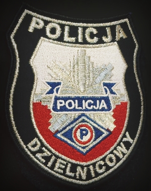 Zbliżenie emblematu tzw. garnizonówki z napisem dzielnicowy