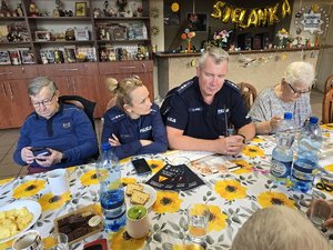 Dwójka policjantów przy stole z seniorami