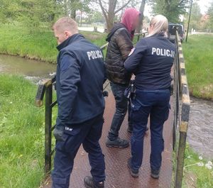 Na wąskiej kładce nad potokiem dwójka policjantów oraz mężczyzna