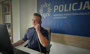 Dzielnicowy asp. Mariusz Wilewski za biurkiem rozmawia przez telefon