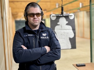 Policjant ze słuchawkami na uszach i w okularach w pomieszczeniu strzelnicy