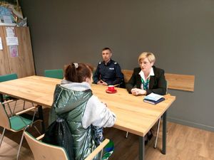 Rozmowa dwóch kobiet i policjanta siedzących przy stoliku