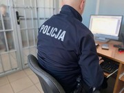 Umundurowany policjant siedzący przed monitorem