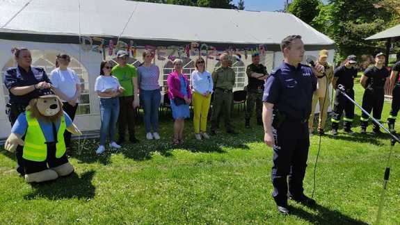 Policjant przy mikrofonie na festynie w tle namioty