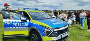 Grupa ludzi z dziećmi wokół radiowozu na pikniku