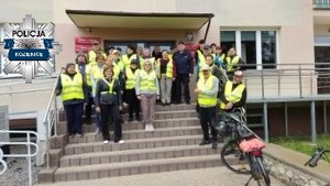 Grupa osób ubranych w żółte kamizelki odblaskowe pozująca do zdjęcia na schodach do budynku