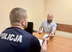 W pomieszczeniu biurowym przy biurku policjant oraz mężczyzna w średnim wieku