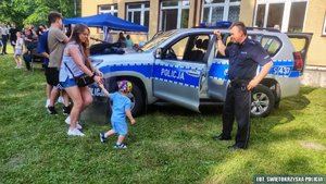 Policjant przy radiowozie terenowym na pikniku rodzinnym