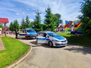 Piknik szkolny, na pierwszym planie dwa radiowozy