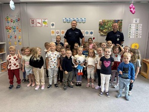 Dwaj policjanci pozujący z dziećmi do zdjęcia wewnątrz sali
