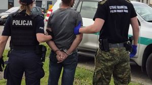 Policjantka ze strażnikiem granicznym trzymają zatrzymanego