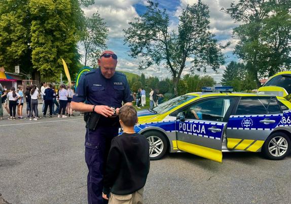 Na festynie policjant z chłopcem w tle pootwierany radiowóz