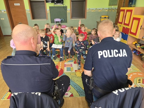 Dwaj policjanci w trakcie pogadanki dla dzieci w sali przedszkolnej